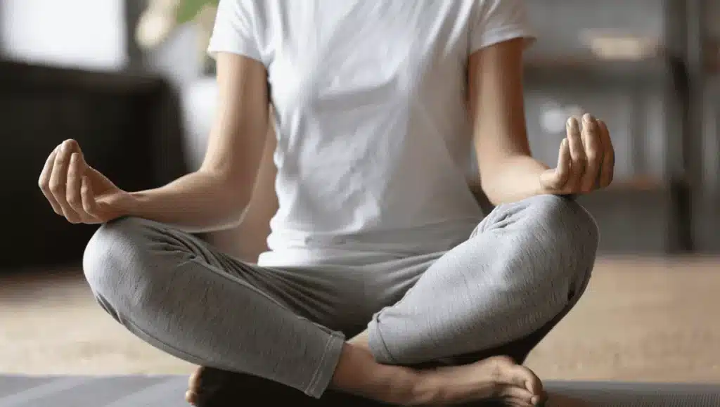 Close-up of a person sitting cross-legged in a meditation pose, symbolizing mindfulness, relaxation, and the mind-body connection.